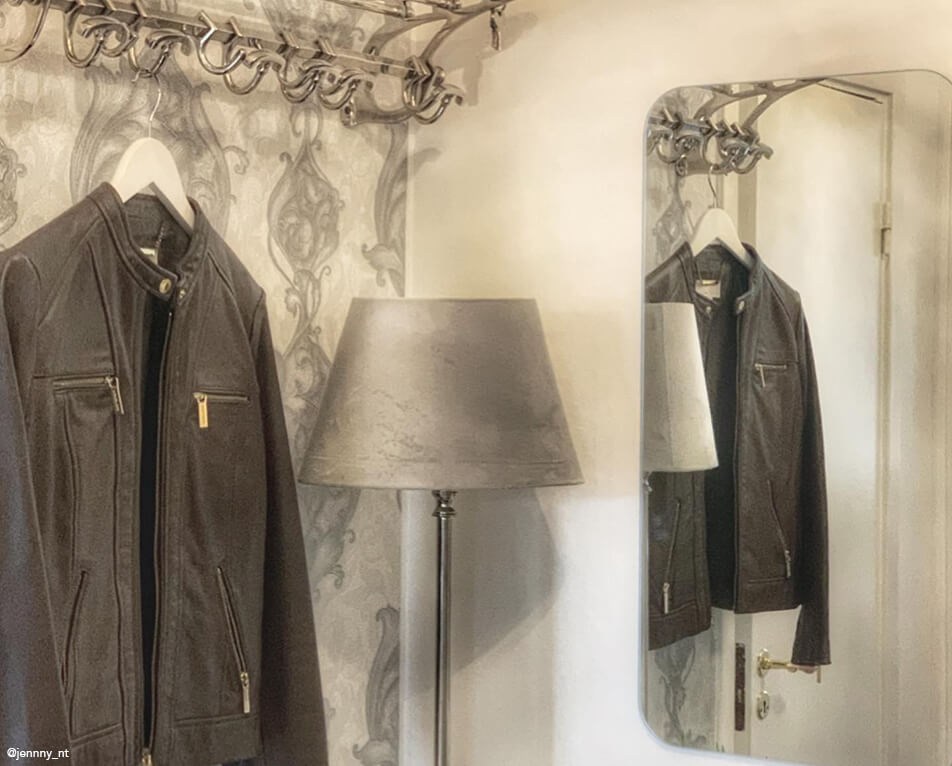 Prieškambario interjeras – metalinė kabykla, stačiakampis veidrodis ir pilka lempa