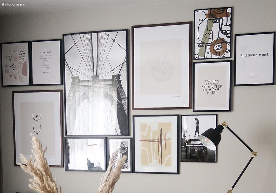 Didžiulė paveikslų siena virš sofos svetainėje